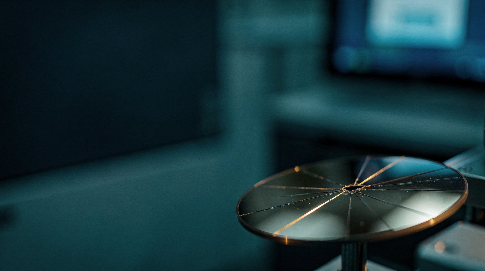 A single wafer with a fine hairline crack across it, the crack catching warm gold light